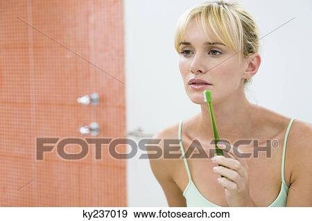 Reflection of a woman in the mirror holding a toothbrush View Large Photo Image Stock Photo - Reflection of a woman in the mirror holding a toothbrush. Fotosearch