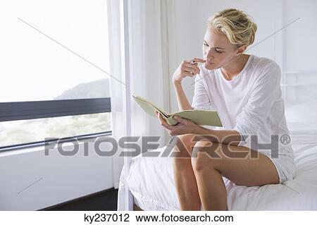 Stock Image - Woman checking a notebook in a bedroom. Fotosearch