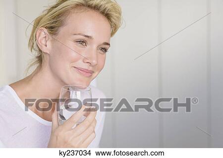 Woman holding a glass of water View Large Photo Image Picture - Woman holding a glass of water. Fotosearch