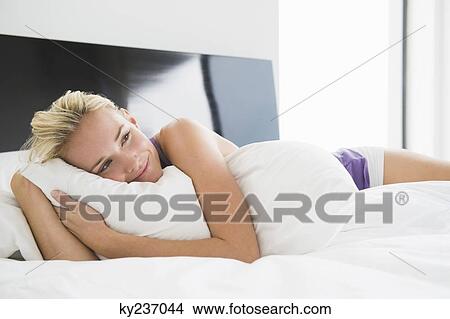 Woman hugging a pillow on the bed View Large Photo Image Picture - Woman hugging a pillow on the bed. Fotosearch