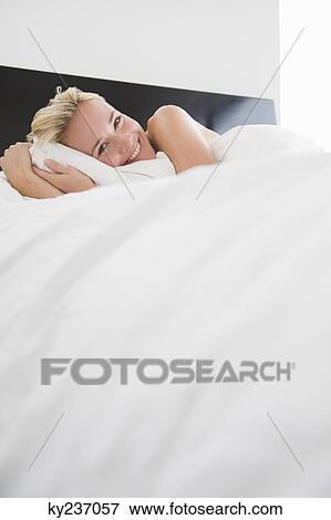 Woman hugging a pillow on the bed View Large Photo Image Stock Photo - Woman hugging a pillow on the bed. Fotosearch