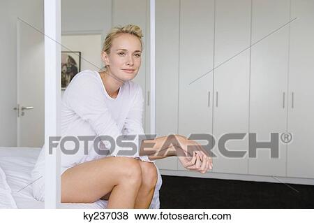 Woman sitting on the bed and smiling View Large Photo Image Stock Photo - Woman sitting on the bed and smiling. Fotosearch