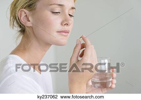 Stock Image - Woman taking an Omega-3 capsule. Fotosearch