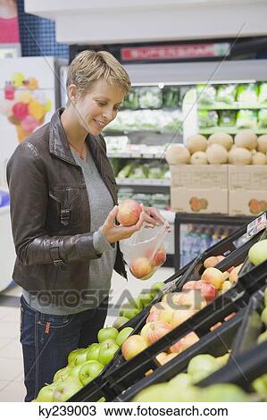 Woman buying apples in a supermarket View Large Photo Image Stock Image - Woman buying apples in a supermarket. Fotosearch