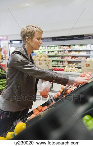 Woman buying vegetables in a supermarket View Large Photo Image Stock Image - Woman buying vegetables in a supermarket. Fotosearch