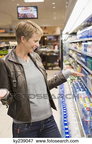 Woman buying water bottle in a store View Large Photo Image Stock Photo - Woman buying water bottle in a store. Fotosearch