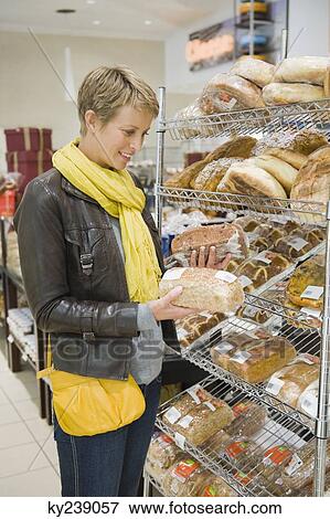Stock Photo - Woman choosing breads in a supermarket. Fotosearch