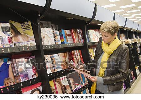 Woman choosing magazines in a supermarket View Large Photo Image Stock Photograph - Woman choosing magazines in a supermarket. Fotosearch