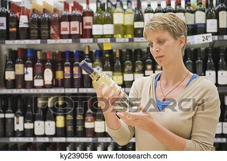 Woman reading a label of a wine bottle View Large Photo Image Stock Photograph - Woman reading a label of a wine bottle. Fotosearch
