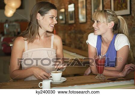 Two women having beverages in a cafe View Large Photo Image Stock Image - Two women having beverages in a cafe. Fotosearch