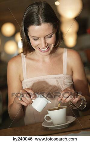 Woman adding milk in coffee in a cafe View Large Photo Image Stock Photograph - Woman adding milk in coffee in a cafe. Fotosearch