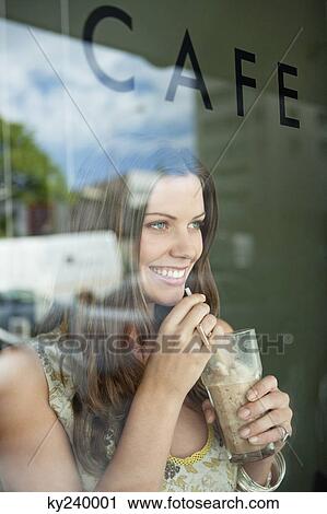 Stock Image - Woman drinking chocolate milkshake in a cafe. Fotosearch