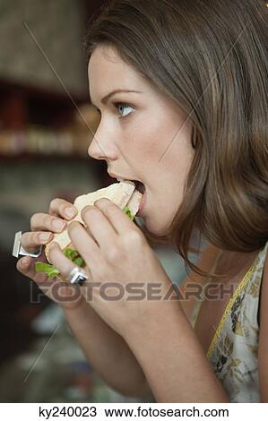 Woman eating sandwich in a cafe View Large Photo Image Stock Image - Woman eating sandwich in a cafe. Fotosearch
