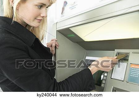 Woman inserting a credit card into ATM View Large Photo Image Picture - Woman inserting a credit card into ATM. Fotosearch