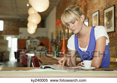 Woman reading a magazine in a cafe View Large Photo Image Stock Photography - Woman reading a magazine in a cafe. Fotosearch