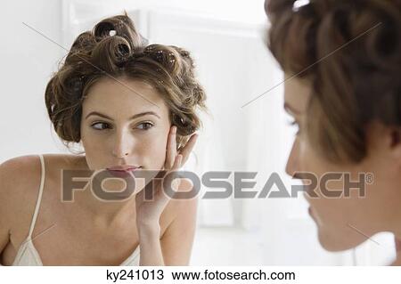 Woman examining her face in the mirror View Large Photo Image Stock Image - Woman examining her face in the mirror. Fotosearch