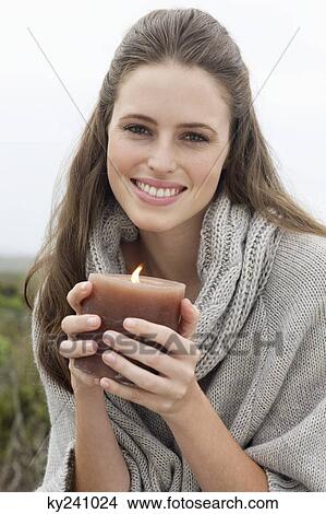 Woman holding a lit candle and smiling View Large Photo Image Picture - Woman holding a lit candle and smiling. Fotosearch