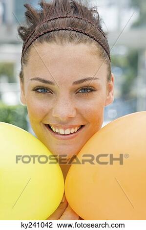 Stock Image - Woman holding balloons and smiling. Fotosearch