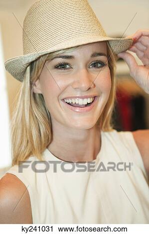 Woman trying on a fedora in a boutique and smiling View Large Photo Image Stock Image - Woman trying on a fedora in a boutique and smiling. Fotosearch