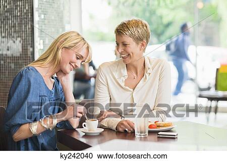 Two women sitting in a restaurant and smiling View Large Photo Image Stock Image - Two women sitting in a restaurant and smiling. Fotosearch