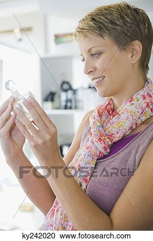 Woman holding a bottle of perfume in a store View Large Photo Image Stock Image - Woman holding a bottle of perfume in a store. Fotosearch