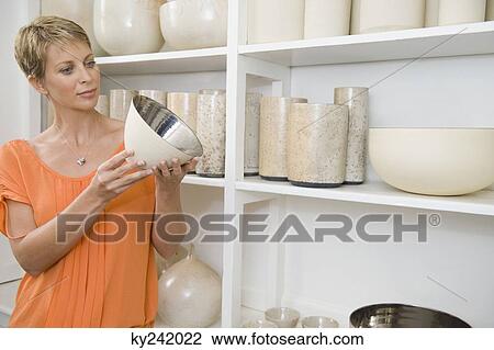 Woman holding a bowl in a store View Large Photo Image Stock Image - Woman holding a bowl in a store. Fotosearch