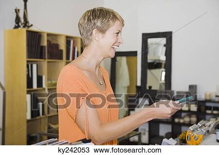 Stock Image - Woman holding a credit card at the checkout counter. Fotosearch