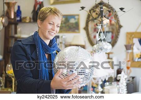 Woman holding a disco ball in a store View Large Photo Image Stock Photography - Woman holding a disco ball in a store. Fotosearch