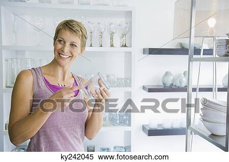 Woman holding a glass in a store View Large Photo Image Stock Photography - Woman holding a glass in a store. Fotosearch