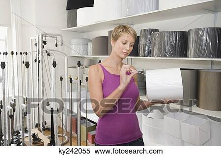Stock Photography - Woman holding a lampshade in a store. Fotosearch