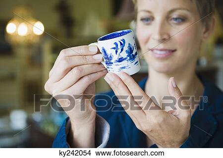 Woman holding a tea cup in a store View Large Photo Image Picture - Woman holding a tea cup in a store. Fotosearch
