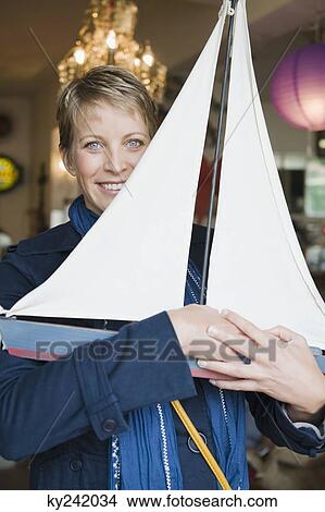 Woman holding a toy boat in a store View Large Photo Image Picture - Woman holding a toy boat in a store. Fotosearch