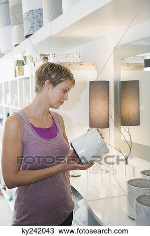 Woman holding a vase in a store View Large Photo Image Stock Image - Woman holding a vase in a store. Fotosearch
