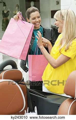 Two women having fun near a car after shopping View Large Photo Image Stock Image - Two women having fun near a car after shopping. Fotosearch