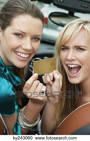Two women showing a credit card in a car View Large Photo Image Stock Image - Two women showing a credit card in a car. Fotosearch