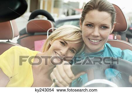 Picture - Two women sitting in a car after shopping. Fotosearch