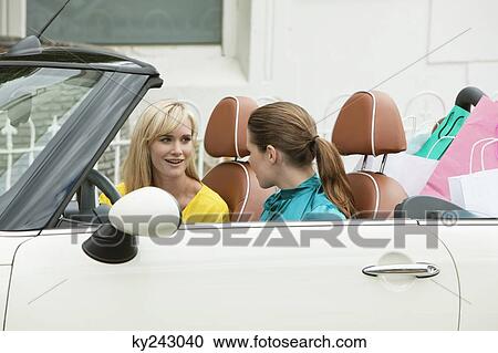 Two women smiling in a car after shopping View Large Photo Image Stock Image - Two women smiling in a car after shopping. Fotosearch