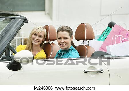 Two women smiling in a car after shopping View Large Photo Image Stock Photograph - Two women smiling in a car after shopping. Fotosearch