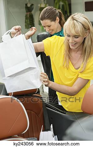 Two women smiling near a car after shopping View Large Photo Image Stock Photograph - Two women smiling near a car after shopping. Fotosearch