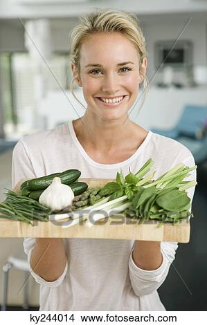 Woman holding vegetables in the kitchen View Large Photo Image Picture - Woman holding vegetables in the kitchen. Fotosearch