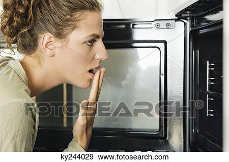 Woman looking shocked near an oven View Large Photo Image Stock Photo - Woman looking shocked near an oven. Fotosearch