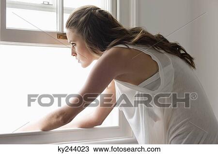 Woman looking through a window View Large Photo Image Stock Image - Woman looking through a window. Fotosearch