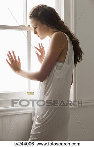 Woman looking through a window View Large Photo Image Stock Photograph - Woman looking through a window. Fotosearch