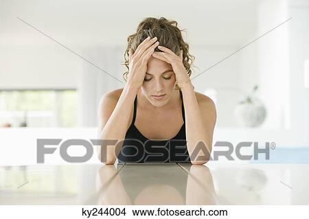 Woman sitting at a table with her head in her hands View Large Photo Image Picture - Woman sitting at a table with her head in her hands. Fotosearch