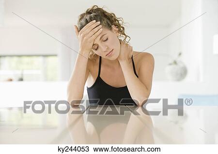 Woman sitting at a table with her head in her hands View Large Photo Image Stock Image - Woman sitting at a table with her head in her hands. Fotosearch