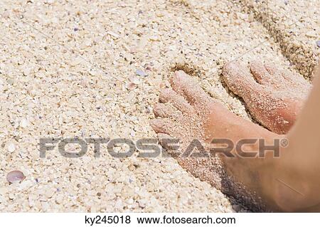 Stock Photo - Close-up of man's feet on sand. Fotosearch