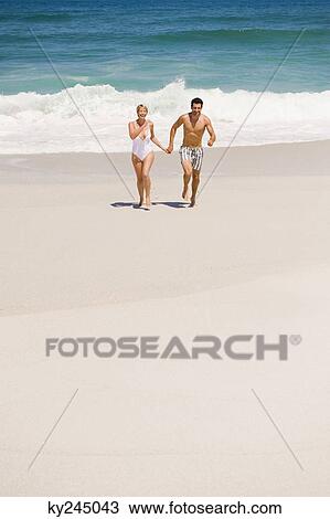 Couple running on the beach View Large Photo Image Stock Image - Couple running on the beach. Fotosearch