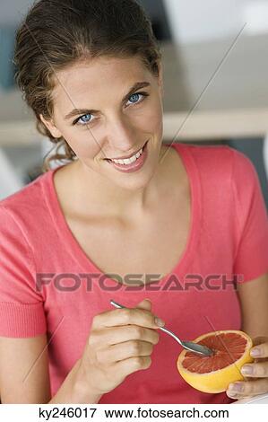 Stock Photo - Portrait of a woman eating grapefruit. Fotosearch