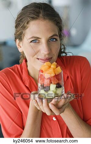 Picture - Portrait of a woman holding fruit salad. Fotosearch