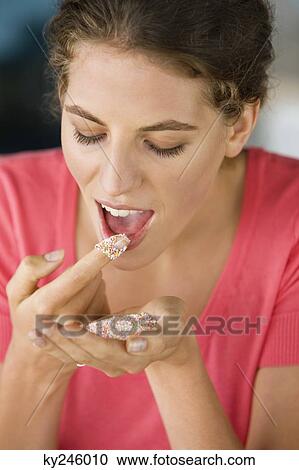 Stock Image - Woman eating colored sugar granules. Fotosearch